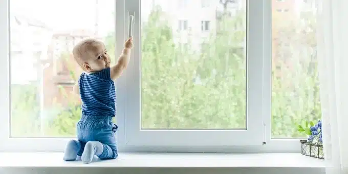 kisgyerek az ablakpárkányon nyitja az ablakot