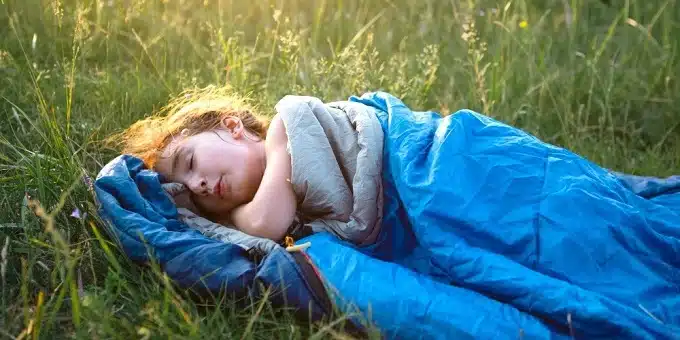 kislány alszik egy mezőn hálózsákban